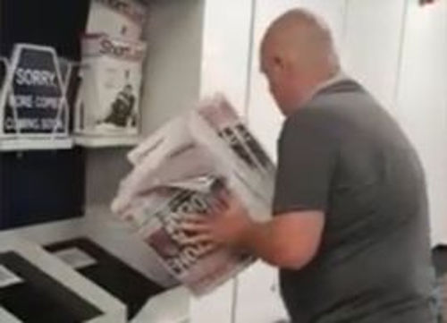 An Everton fan throws all complimentary copies of The Sun in the bin at Glasgow Airport