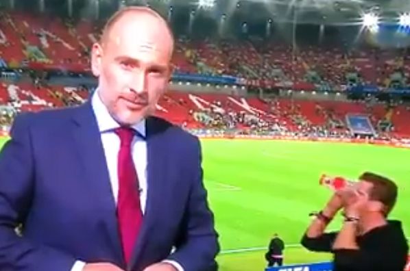 A fan with cups over his eyes walks behind a reporter at Colombia v England in the last 16 of the World Cup in Russia