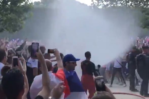 A French fireman sprays supporters with his hose to cool them off after France won the World Cup final