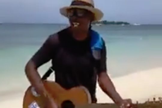 Man with guitar on a beach sings Sh*t on the Villa for a Birmingham City fan in Jamaica