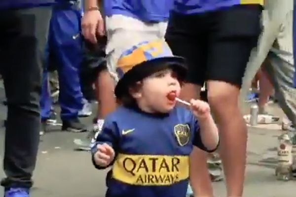A toddler in Boca Juniors kit dances for fans outside La Bombonera before Copa Libertadores final first leg