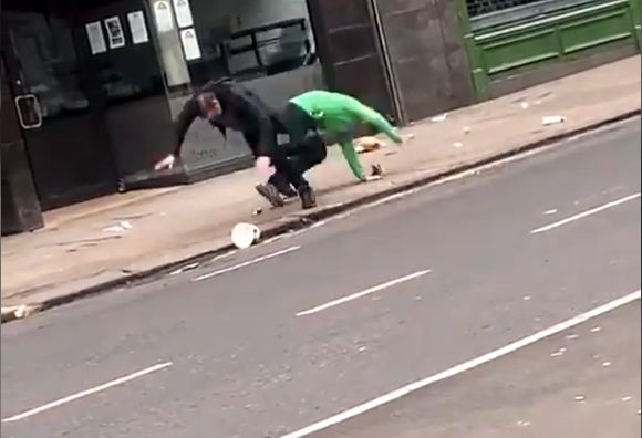 Two drunk men crash to the pavement after tripping each other up playing football with a can